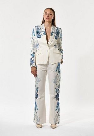 Hvid dragt med blomsterprint i blå; skræddersyet blazer med takkede revers og matchende vide bukser; glat stoftekstur.