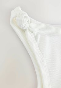 Maillot de bain en tissu côtelé blanc avec un détail noué à l'épaule. Texture lisse avec une coupe ajustée et des bords finis.