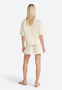 Knit two-piece set in light yellow. Features a loose short-sleeve top and matching shorts with a textured, open weave design.