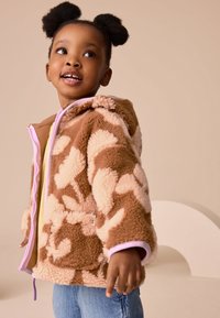 Fleecejack met een bruin-beige bloemenpatroon met roze accenten. Voorzien van een capuchon en ritssluiting, met een zachte, gestructureerde afwerking.