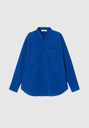 Chemise bleu à manches longues avec boutons, col et poche sur la poitrine gauche, affichée sur un fond gris clair.