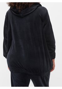 Černá velurová oversized mikina s kapucí na stažení a elastickým lemem. Měkký materiál s dlouhými rukávy, volný střih pro pohodlí.