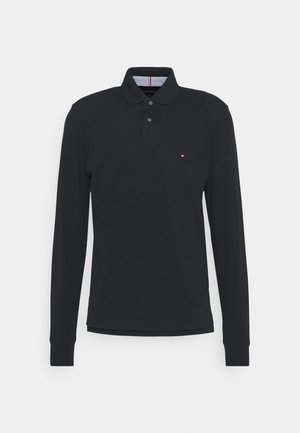 Polo à manches longues bleu marine en coton, avec un col boutonné et un petit logo sur la poitrine. Présente un col interne rayé.