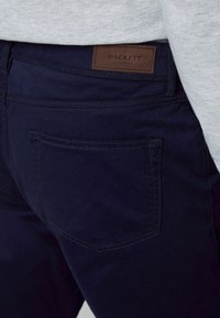 Marineblaue Chinos aus Baumwollmischung, mit einer Gesäßtasche und einem genähten Etikett am Bund mit dem eingeprägten Schriftzug "HACKETT LONDON".