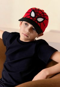 Gorra roja con un diseño de Spider-Man, con acentos en relieve de telaraña negra y ojos blancos, acompañada de una visera negra y detalles bordados.