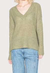 Olivgrüner gestrickter Pullover mit V-Ausschnitt, langen Ärmeln und lockerem Sitz. Die Textur ist weich mit einem lockeren, offenen Strickmuster.