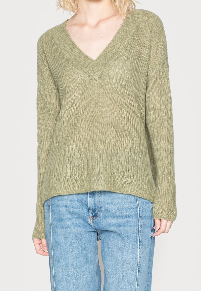 Olivgrüner gestrickter Pullover mit V-Ausschnitt, langen Ärmeln und lockerem Sitz. Die Textur ist weich mit einem lockeren, offenen Strickmuster.