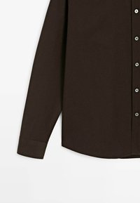 Camicia a maniche lunghe di colore marrone scuro con bottoni visibili e polsini su uno sfondo bianco, tagliata a metà sezione.