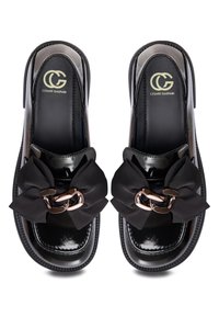 Black patent leather slide shoes with a wide black fabric bow and a decorative metallic chain detail. Features a logo on the insole.