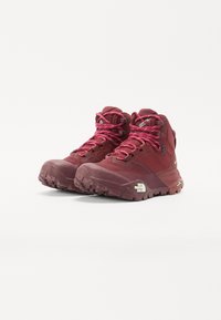 Bordeauxfärgade högskor för vandring med rosa snören, strukturerad gummisula och förstärkt tå. Har en logotyp på sidan och öglor för snörning.