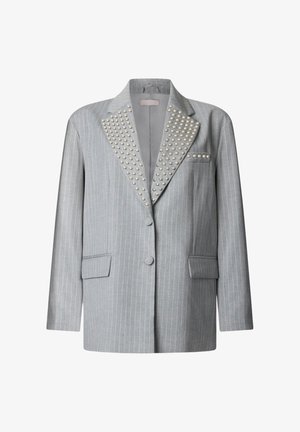 Blazer grigio chiaro a righe sottili con borchie argento sulle ampie rever e sulla tasca sul petto, due tasche frontali con pattina e due bottoni rivestiti di tessuto.