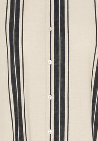 Tissu beige à rayures noires verticales avec cinq petits boutons blancs alignés au centre sur un vêtement.