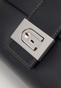 Czarna skórzana torebka z metalowym zapięciem w kolorze srebrnym. Szczegółowe przeszycia wzdłuż brzegów oraz gładka tekstura podkreślają jej design.