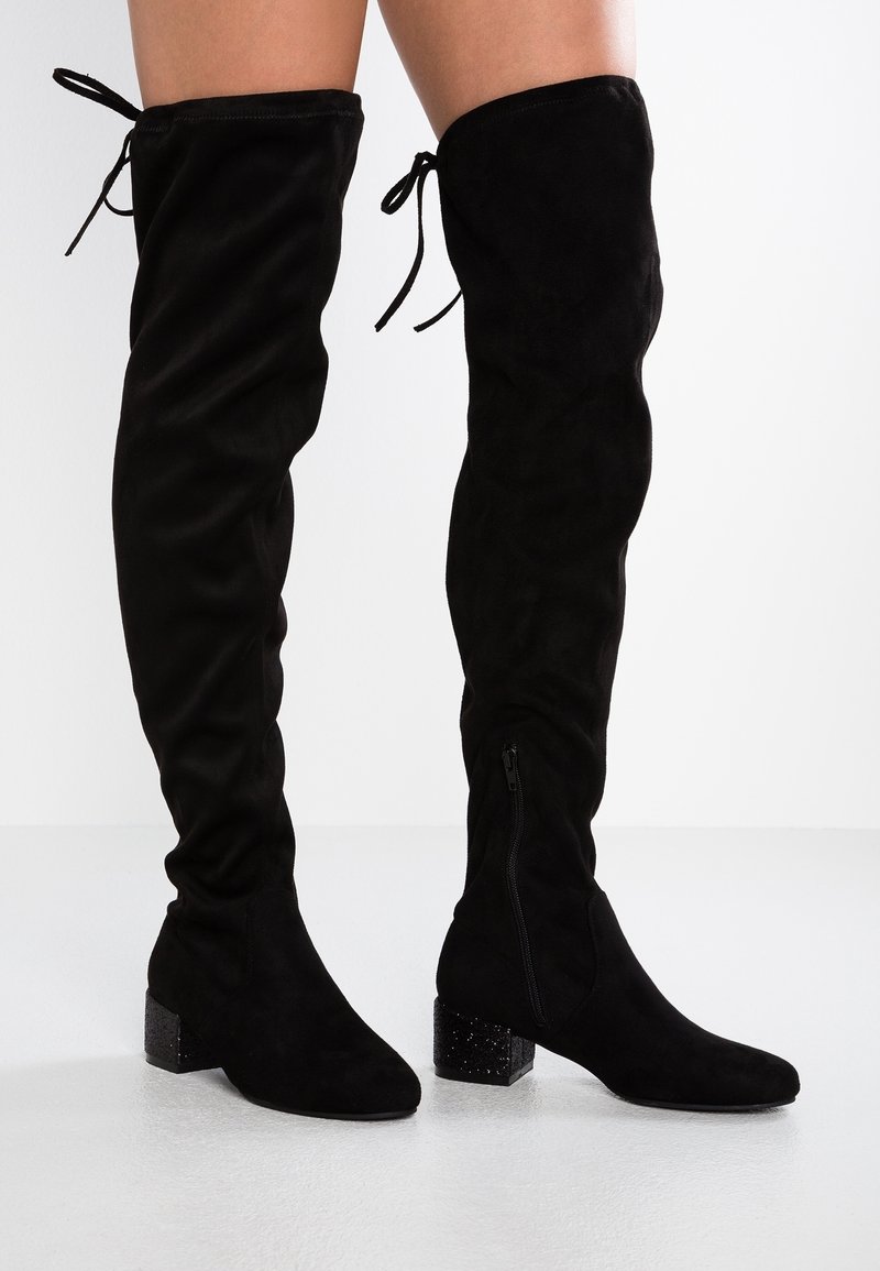 Botas negras de ante sobre la rodilla con punta afilada, tacón cuadrado con detalle de purpurina y cierres ajustables con cordones en la parte superior.
