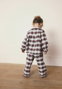 Kariertes Schlafanzugset in Rot und Weiß, bestehend aus einem knöpfbaren Oberteil mit umgeschlagenen Ärmeln und passenden, locker sitzenden Hosen. Strukturierter Baumwollstoff.