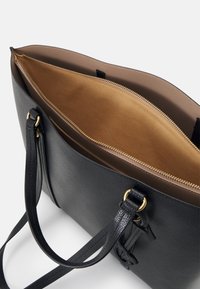 Czarna skórzana torba tote o teksturowanej powierzchni, z złotymi elementami i brązowym wnętrzem. Posiada zamykaną na zamek kieszeń oraz podwójne rączki na ramię.