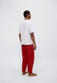 Γκρι βαμβακερό μπλουζάκι με κοντά μανίκια, συνδυασμένο με άνετο κόκκινο παντελόνι φόρμας με ελαστικά μανίκια και πίσω τσέπη.