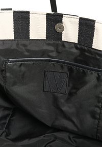 Torbica s prugama u crnoj i bijeloj boji s kopčanjem na dugme, s glatkom crnom podlogom, unutarnjim džepom i reljefnim logotipom.