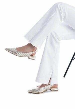 Zapatos slingback metálicos tejidos con punta puntiaguda, pequeño tacón cuadrado y detalle de hebilla, combinados con jeans blancos de pierna ancha.