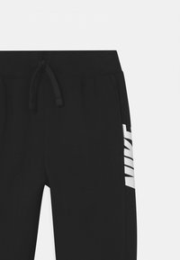 Svarta sweatpants tillverkade av mjuk tyg, med dragsko i midjan och en vit logotyp tryckt vertikalt på vänster sida.