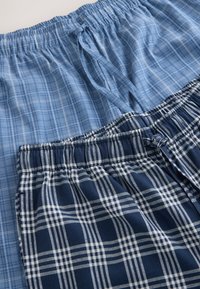 Two pairs of plaid-patterned cotton shorts in light blue and navy, each with elastic waistbands and drawstring ties.
