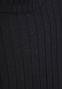 Zwarte ribgebreide stof met verticale gestructureerde strepen en een brede kraagrand.