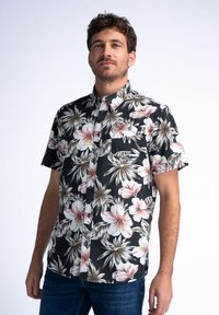 Camisa de manga corta botonada en tejido negro, con grandes patrones florales en blanco y rosa, y un bolsillo en el pecho con un botón.