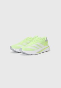 Scarpe da atletica verde lime con strisce bianche, tomaia in rete e accentuazione grigia sul tallone. Design leggero e suola texturizzata per una migliore aderenza.