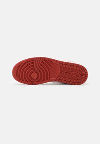 Soletta in gomma rossa con motivi di battistrada circolari e lineari; presenta un logo Nike vicino al tallone e una superficie texturizzata per una migliore aderenza.