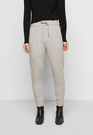 Ljust gråa sweatpants med dragsko i midjan, sidfickor och något avsmalnande ben, kombinerade med en svart figurnära långärmad topp.