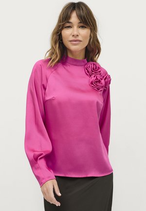 Roze satijnen blouse met lange mouwen, hoge halslijn en driedimensionale rozenapplicaties aan de linkerkant. Soepele textuur en aansluitend ontwerp.