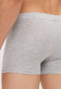 Szürke pamut boxeralsó, elasztikus derékrésszel, puha tapintással és testhezálló fazonnal, amely a comb közepéig ér.
