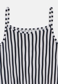 Stribet tanktop med tynde sorte og hvide lodrette striber, lavet af blød bomuld, med justerbare spaghetti-stropper og rundet halsudskæring.