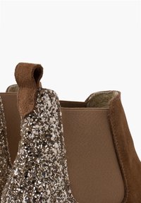 Bruine enkellaarsjes met een glinsterende gouden en zilveren neuskap, vervaardigd uit suede en elastisch materiaal. Inclusief een lus bij de hiel voor extra ondersteuning.