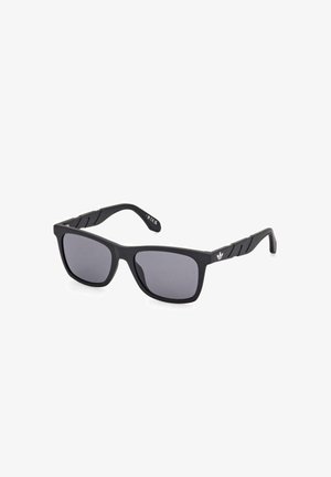Gafas de sol rectangulares negras con lentes oscuros y brazos texturizados que presentan un pequeño logotipo blanco de Adidas en el costado.