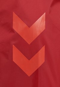 Twee naar beneden gerichte rode chevrons op een gestructureerde rode stoffen achtergrond, die richting of designdetail suggereren.