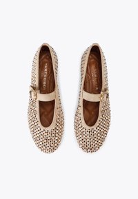 Scarpe Mary Jane in suede beige, decorate con strass trasparenti. Punta arrotondata, suola piatta, con una piccola fascetta laterale con fibbia.