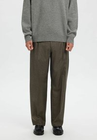 Hall triiksärk soonikkoes varrukate ja pruuni ruudulise laiade jalgadega pükstega, mida täiendab mustad pidulised kingad.