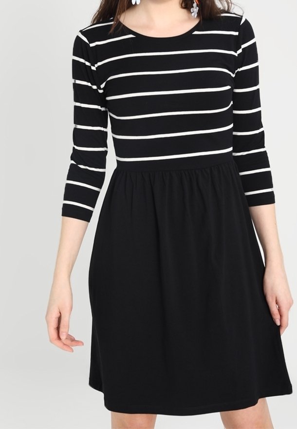 Schwarzes Kleid mit weiß gestreiften Dreiviertelärmeln. Eng anliegender Oberkörper geht in einen ausgestellten Rock über. Weicher Stoff mit glatter Textur.