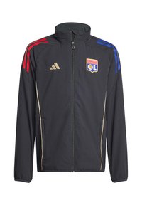 Zwarte sportjas met rode en blauwe strepen op de mouwen, gouden accenten en het logo van Olympique Lyonnais. Voorzien van een rits en zijzakken.