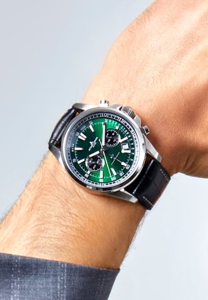 Reloj cronógrafo de acero inoxidable plateado con esfera verde, subesferas negras y correa de cuero negra. Cuenta con manecillas y marcadores luminosos.