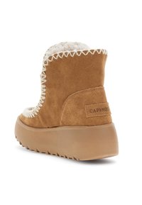 Hnědé semišové kotníkové boty s tlustou gumovou podrážkou, bílým prošíváním a bílým chlupatým podšívkou, viděné z úhlu zezadu.