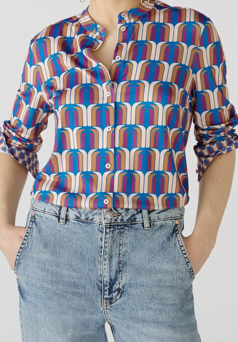 La camicia button-up colorata presenta un motivo multicolore di archi in rosa, blu e beige, con colletto arrotondato e maniche lunghe arrotolate.
