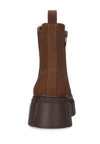 Braune Wildleder-Ankle Boots mit einer dicken Plattformsohle, ausgestattet mit einer Zuglasche an der Rückseite und dezenten Steppnähten entlang der Nähte.