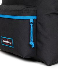 Zaino nero con zip e cordino blu, dotato di una tasca frontale e un'etichetta con il logo Eastpak. Il materiale sembra resistente con una finitura testurizzata.