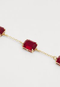 Pulsera de cadena de oro que presenta cuatro piedras preciosas rojas rectangulares con facetas, engastadas en garras de oro, unidas por delicadas cadenas de oro.