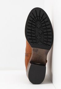 Stivale alla caviglia in suede marrone con suola in gomma nera testurizzata, caratterizzato da un motivo a zig zag e un tacco piccolo. Taglia contrassegnata come 37.