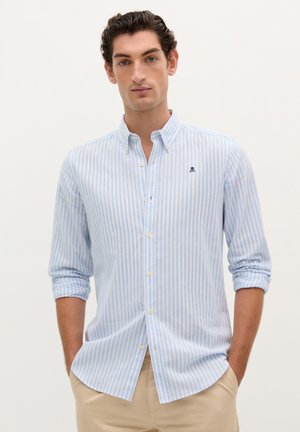 Light blue and white striped button-up shirt, long sleeves rolled, soft cotton fabric, small logo on chest, casual design.