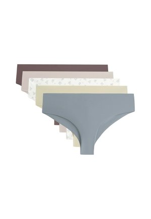 Femme portant un sous-vêtement hipster beige sans couture, montrant le bas de l'abdomen et le haut des cuisses sur un fond neutre.