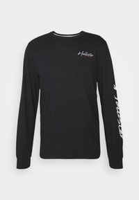 Svart långärmad t-shirt i bomull med en vit logotyp på bröstet och text längs den högra ärmen. Standard design med rund hals.